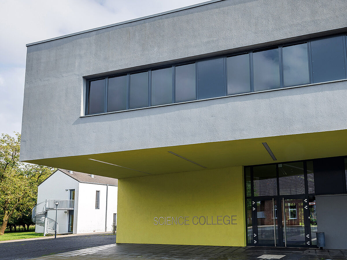 Haupteingang des Science Colleges, ein modernes Gebäude in neongrün und grau.