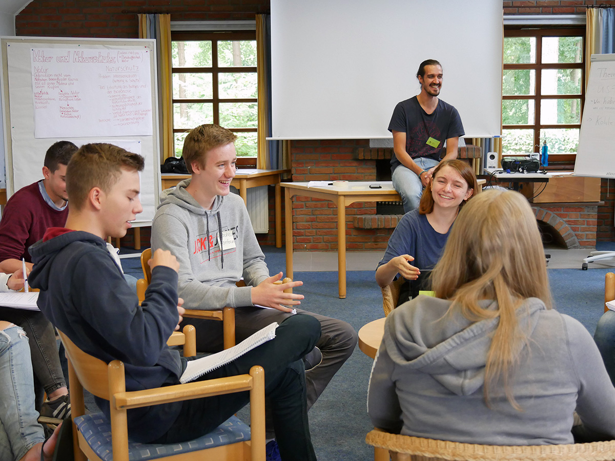 Junge Menschen sitzen in einem Stuhlkreis und diskutieren.