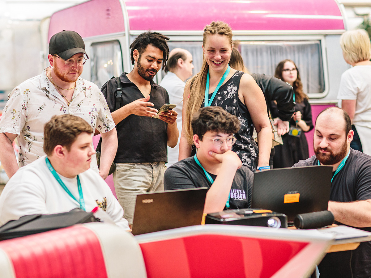 Eine Gruppe junger Menschen schaut auf zwei Laptops.